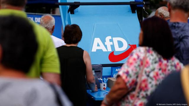 The logo of far-right Alternative for Germany (AfD) party is seen on a stand as supporters gather for an AfD election campaign meeting in Weisswasser, Saxony, eastern Germany on August 14, 2024