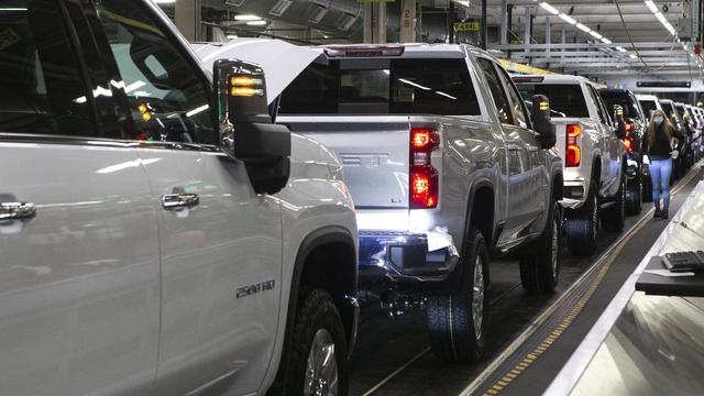 Des camionnettes Silverado dans la chaîne d'assemblage et une travailleuse à l'usine de GM à Oshawa, le 22 février 2022.