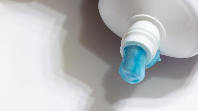 blue toothpaste oozing from a white tube blue toothpaste oozing from a white tube