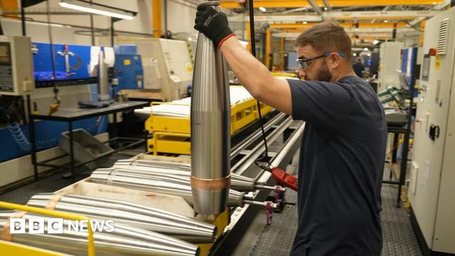 Man holding a shell casing in a BAE factory