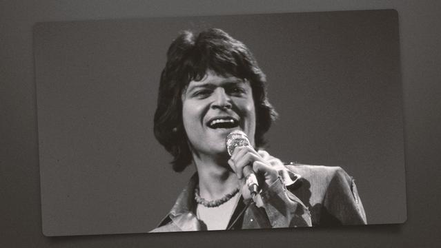 Johnny Rodriguez singing with a microphone