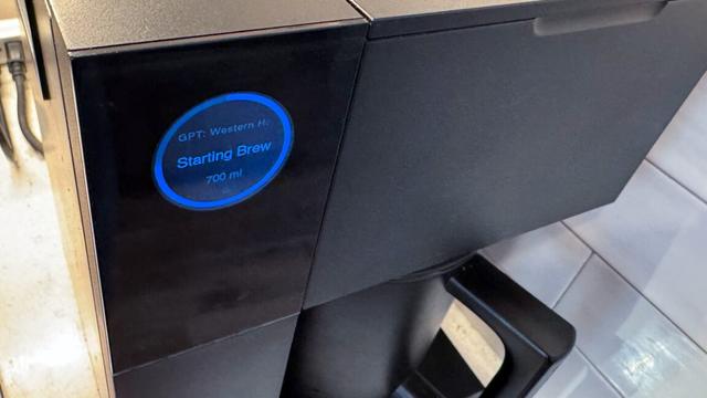 A Fellow Aiden coffee brewer, showing a blue circle on its circular screen, with "Starting brew: GPT: Western House" in text.