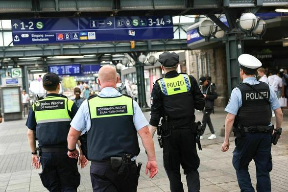 Vier Männer unterwegs am Hauptbahnhof in Hamburg: zwei Männer vom Sicherheitsdienst in Uniform und zwei Polizisten, die bewaffnet sind