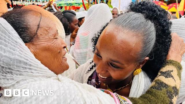 A close up of two women hugging and smiling.
