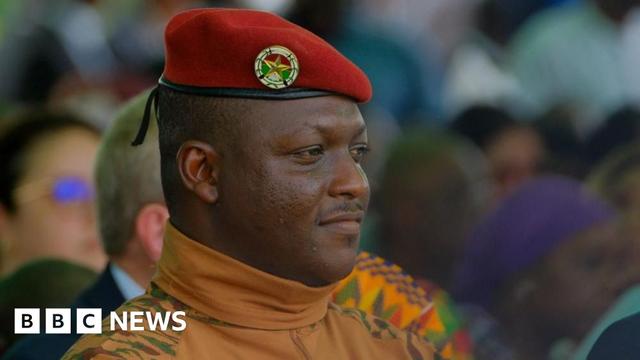 A head and shoulders shot of Burkina Faso's military leader Ibrahim Traore. He is wearing a red military beret and a camouflage roll-neck top.