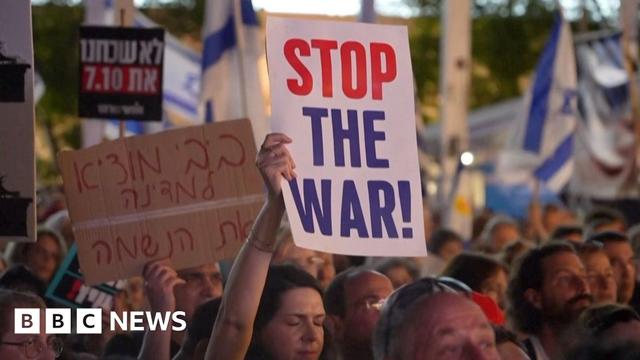 Protesters march holding aloft signs, one reads 'Stop the war!'