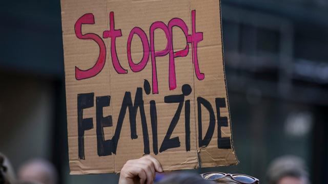 Eine Teilnehmerin einer Demonstration hält ein Schild mit der Aufschrift "Stoppt Femizide"