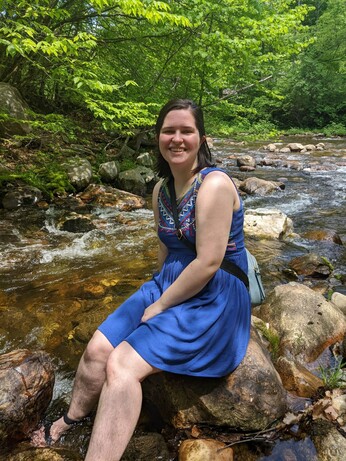 Clare sitting on a rock by a creek
