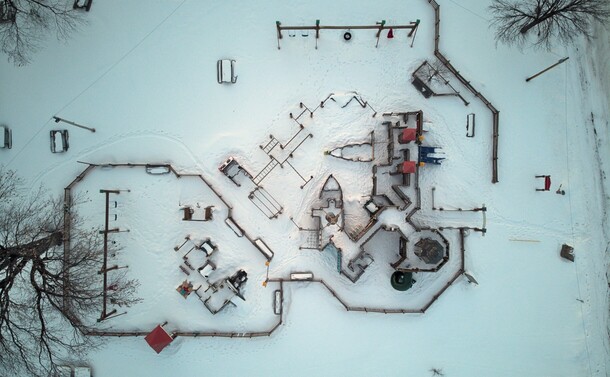 Looking down on playground in Crosby, Minnesota park. The ground is covered in snow and you can see the outline of each area of playground. 
