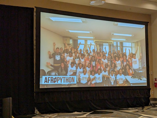 Crowd shot of the first AfroPython event showing roughly 30 people holding their hands up in celebration