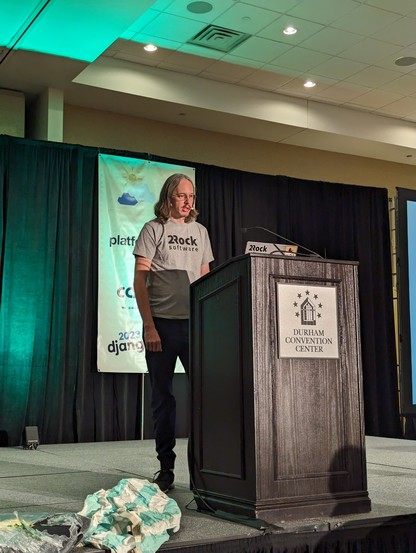 Peter at the podium wearing a gray two rock software shirt