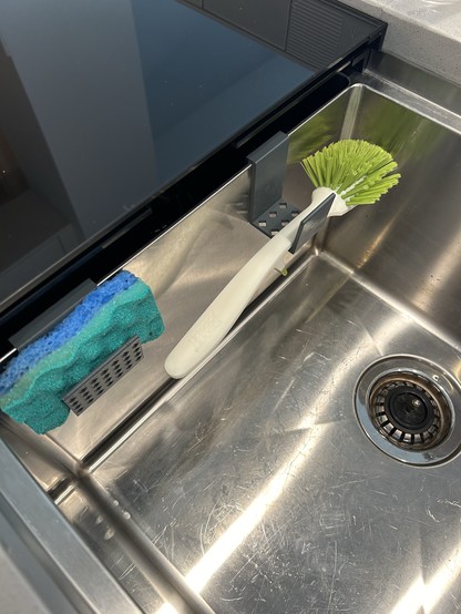 A sink with a dish brush and a sponge holder. 