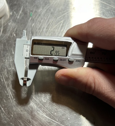 A small cylindrical magnet jn digital calipers reading 2.95