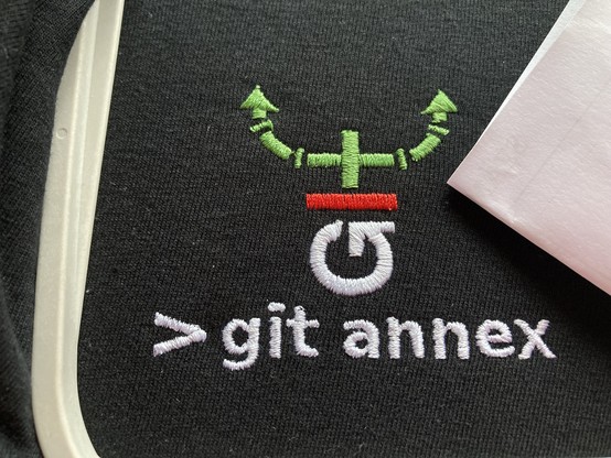 black shirt with colourful git annex logo and '> git annex' written below, embroidered, picture by Gabor Kum, hellotux.com