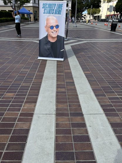 A banner with howie mandel on it that says “security line starts here”