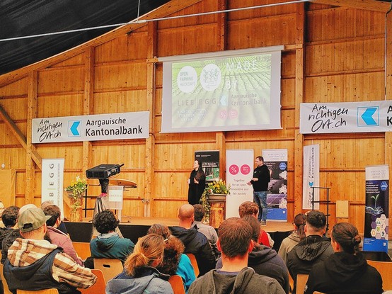 Darienne and Yannick on stage at the opening of the hackathon with a bunch of people participating 