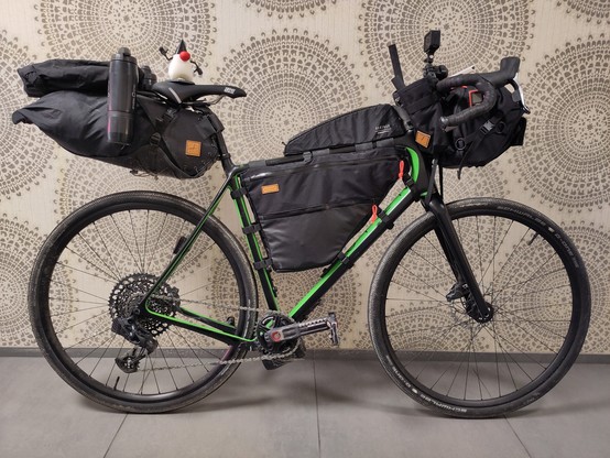 A fully packed Gravel bike cramped with bags and the Java mascot "Duke" sitting on the saddle.