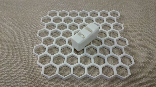 One plate of honeycomb storage wall layed flat with one keyguardian (a cuboid with two parallel slots) attached at the center. A hand brings in two little 'keys' connected via a string and puts one key into the keyguardian, which locks the key there. The other key now has a limited movement radius. When the free key is inserted into the other keyguardian slot, the first key is ejected and now has its own limited movement radius.