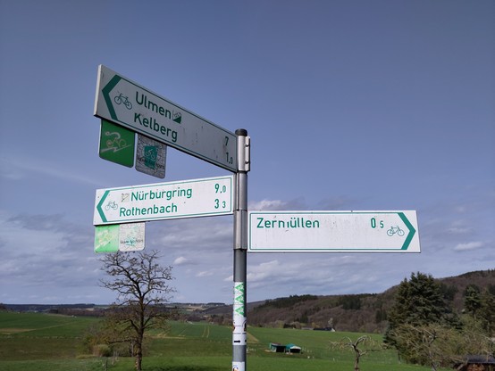 Ein Wegweiser mit ganz vielen Angaben. Eine davon lautet "Nürburgring 9 km".