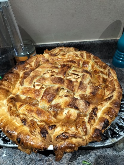 a lattice pie on a kitchen-top, golden brown and bubbling.