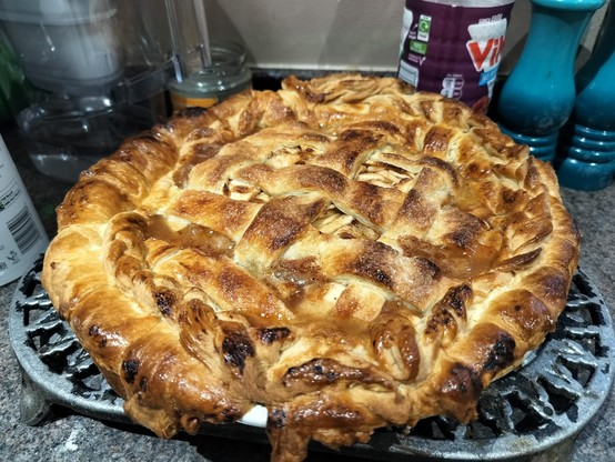 a lattice pie on a kitchen-top, golden brown and bubbling. wider shot.