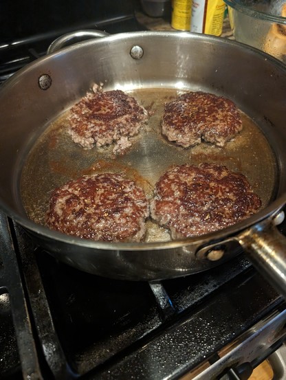 4 lamb burger patties on a skillet