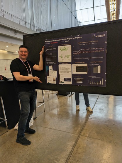 A tall guy named Vince Salvino is standing next to a poster that is labeled building accessible websites with Wagtail and Django.