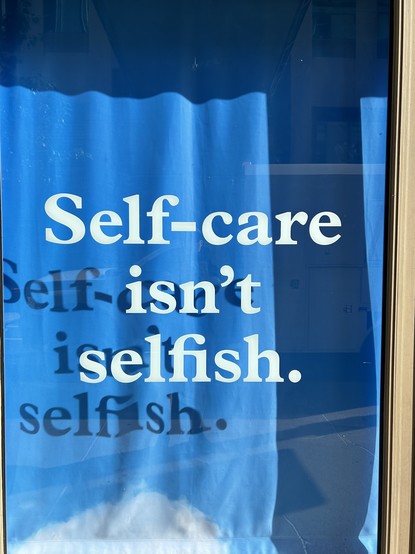 Message in a shop window reading “self-care isn’t selfish”