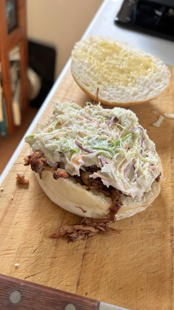 White bun, buttered, with pulled pork and coleslaw