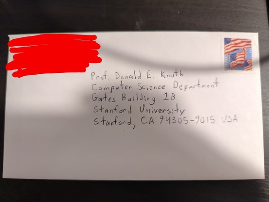 An sealed and stamped envelope with the return address obscured (not that I'm under the illusion that my address is particularly private), addressed to

Prof. Donald E. Knuth
Computer Science Department
Gates Building 1B
Stanford University
Stanford, CA 94305-9015 USA