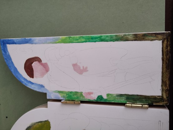 Held at an angle, the panel now has a border with a gradient from dark brown to green to blue, to symbolize earth to heaven. In the middle of the panel (a side-panel, the right-hand one) are the beginning of a face and two hands, but that needs to be painted in some more.