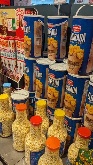 large  containers of chips (crisps) and popcorn. the popcorn is probably a few litres of popped corn, and the chips are large enough to require a handle on the tubular container