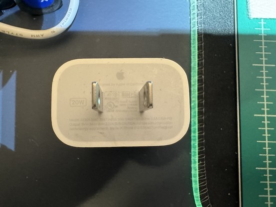 Apple power adapter with barely legible markings.