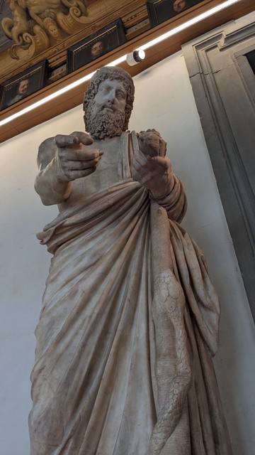 statue of Aesclepius pointing his finger at the camera