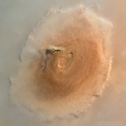A dust storm seen on the tallest volcano of Mars, Olympus Mons. Surface is rusty red and the surrounding of the volcano is pretty cloudy.