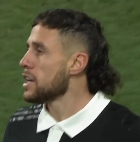 T J Perenara, with an appalling haircut. It's not even a mullet, it's a bit of hair on top, shaved on the sides, and then a lump of hair on the back of his head. Vile. His black shirt has a white collar, which would be fine, but then he there's a single preaching tab down the front which just makes it look weird.