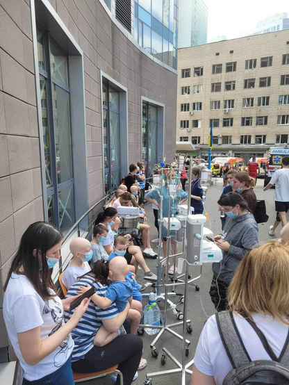 Dozens of children with cancer on the street with lots of medical equipment