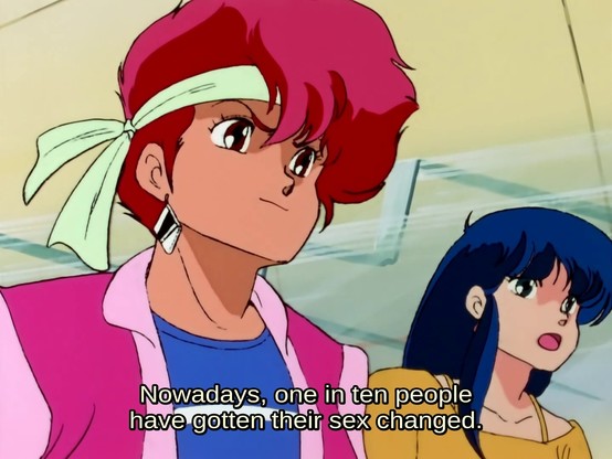A screenshot from the anime Dirty Pair. Both of the protagonists are visible, Kei is dressed with a pink jacket and blue shirt and a white headband. Yuri has a yellow dress. She's talking and the caption says: 