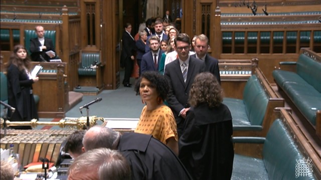 A queue of MP's leading into the centre of the house of commons with ushers dotted around
