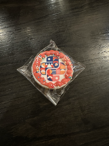 Small round cookie decorated with the EuroPython 2024 logo and a pink decoration around it.