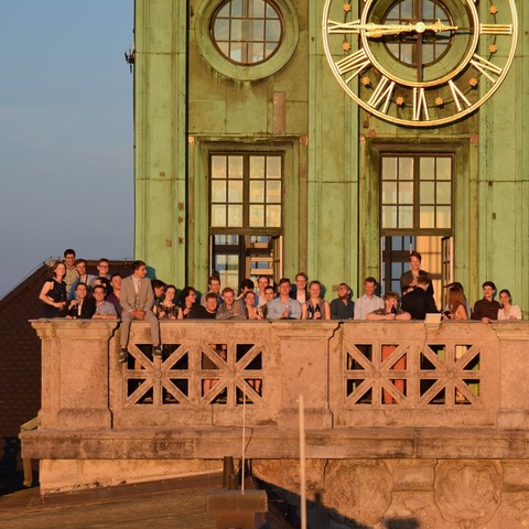 Members of our student club are standing on the balcony of the clock tower during sunset 