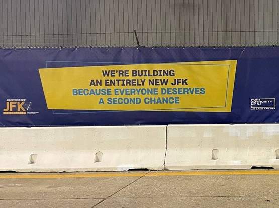 Construction site banner for JFK airport proclaiming:

