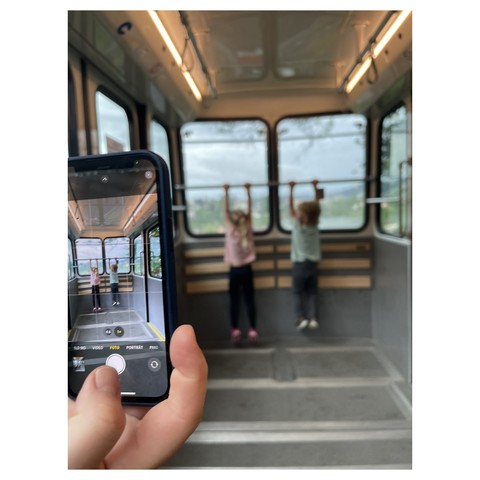 Photo of a phone taking a photo of two kids in a gondola…