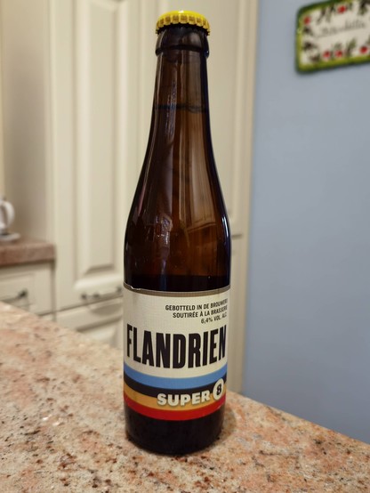 A tall bottle of Flandrien Super 8 beer on a kitchen counter.