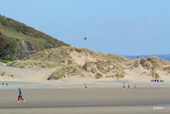 People enjoying a day on the beach.  A perfect day for children to 'go fly a kite'.