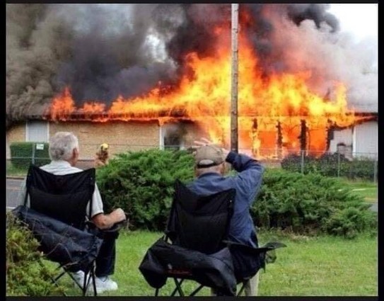 Two old blokes in lawn chairs watching a massive fire burning.