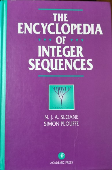 Shot of the cover of the 1995 book The Encyclopedia Of Integer Sequences, by N. J. A Sloane, and Simon Plouffe.

The cover is an intense purple, with white lettering and teal border markers, and a teal, white, and purple illustration of an inverted binary tree with the number sequence 