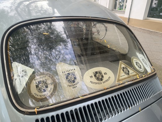 Rear window of a car covered in stickers from the Bayreuth Festival, dating from 1980 to 1990.