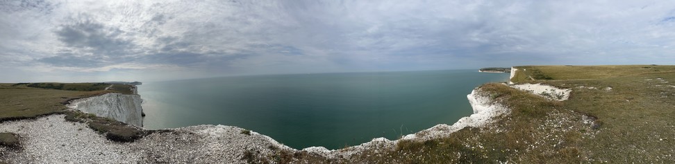 A panoramic view out to the azure sea from atop one of the Seven Sisters. Chalky floors give way to grassy slopes. 