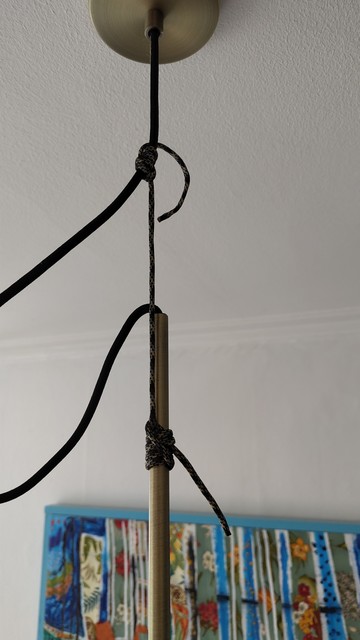 Ceiling lamp hanging by a cable shortened by parachute cord and two Blake's Hitches - the cord is tied to two points in the hanging cable and then the knots are pushed farther apart, leaving slack in the cable and the lamp hanging by the now-shorter cord.

A friction hitch holds on to another rope and allows sliding when you push the knot, but holds when you pull the working end.  So, this is adjustable on both ends but if you pull on it, it holds plenty of weight.  A friction hitch isn't traditionally tied around a solid object like you see on the bottom (bottom is actually attached to the metal lamp tube, but it's not that unusual.

Blake's hitch is quite good but not the easiest to start with.

Wikipedia is a good starting point for details on most knots.

